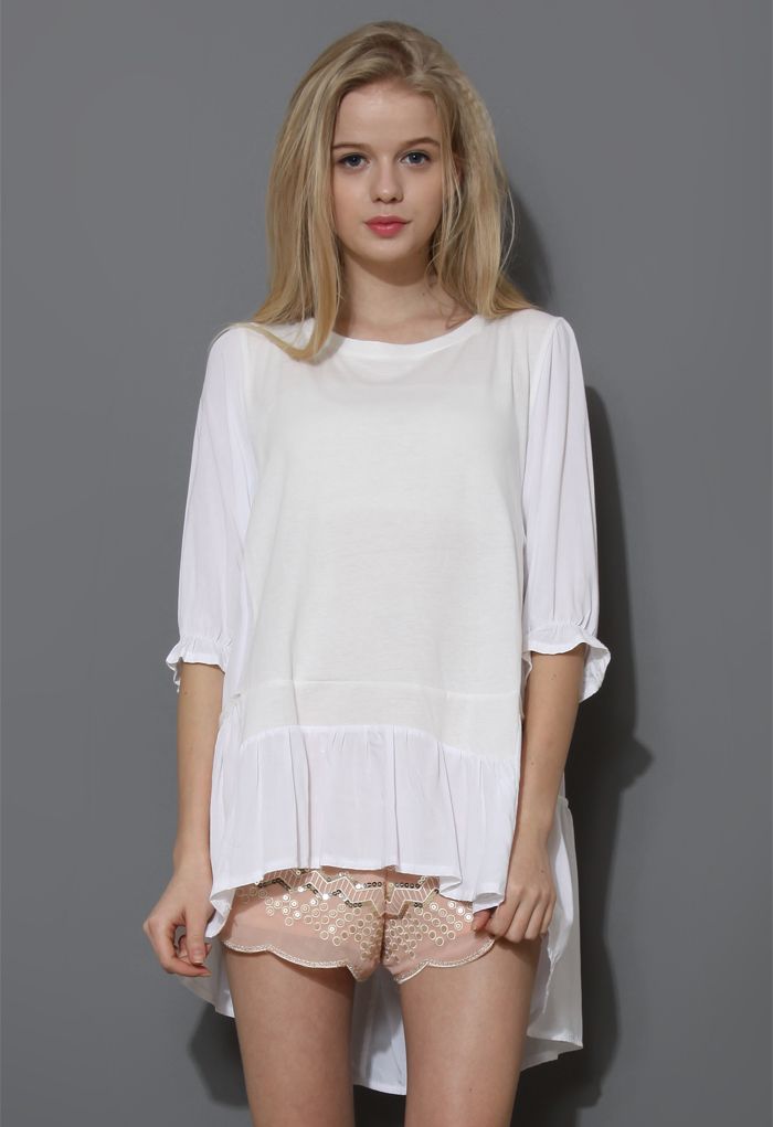 Front view of a cozy white dolly hi-lo top with a relaxed fit, featuring three-quarter sleeves and ruffled hem for a romantic, casual look.