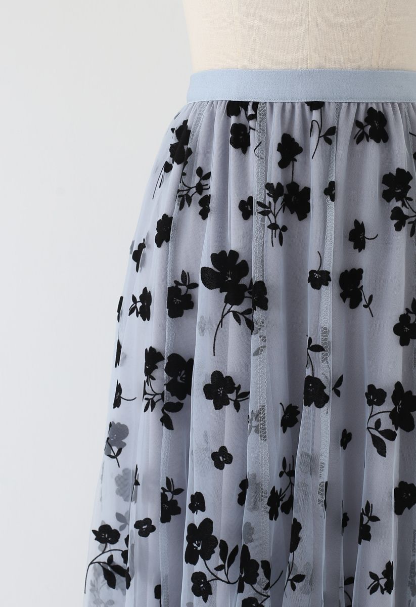 Detail shot of a dusty blue mesh midi skirt featuring black floral designs and a light blue waistband.