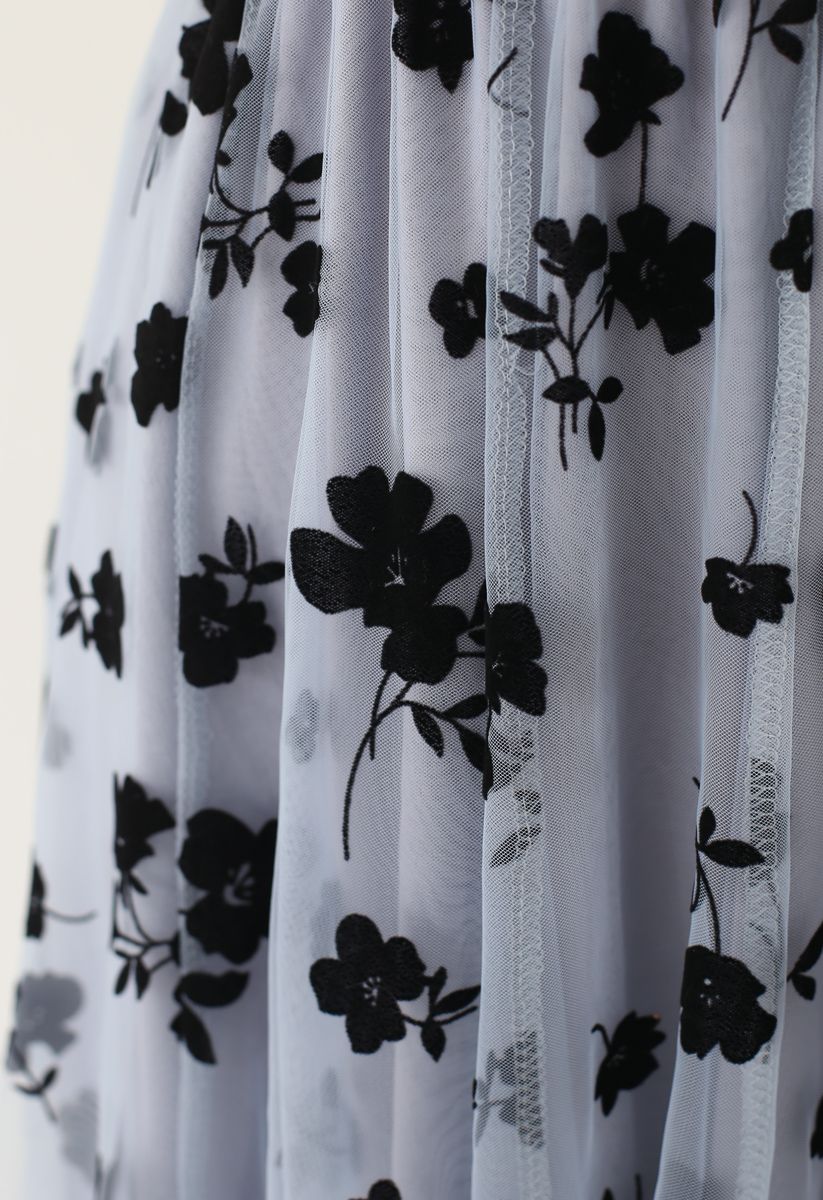 Close-up of a dusty blue mesh skirt showcasing the intricate black floral patterns and sheer fabric.