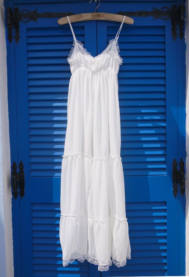 Front view of a vintage-inspired white maxi chiffon dress with lace detailing, displayed on a hanger against a blue background.