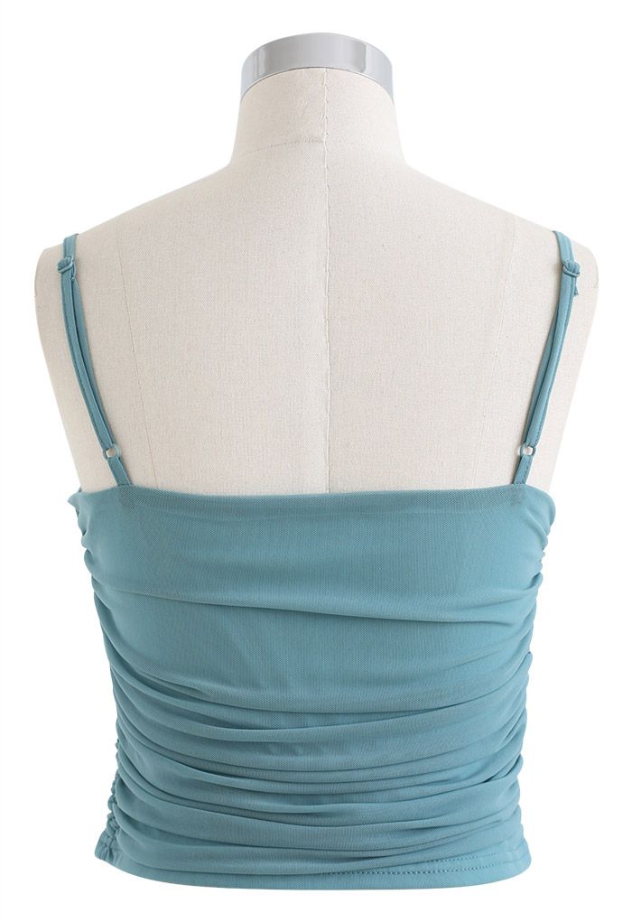 Back view of a teal ruched soft mesh cami top on a mannequin, featuring adjustable straps and a smooth finish.
