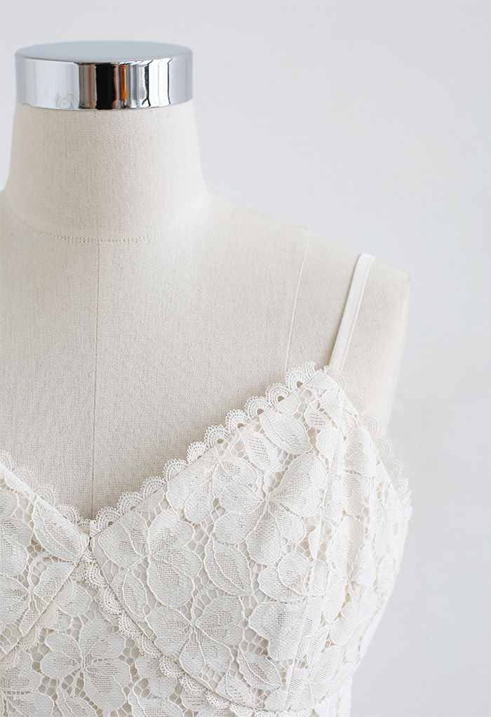 Detail shot of a white lace crop cami top on a mannequin, highlighting the intricate floral lace pattern.