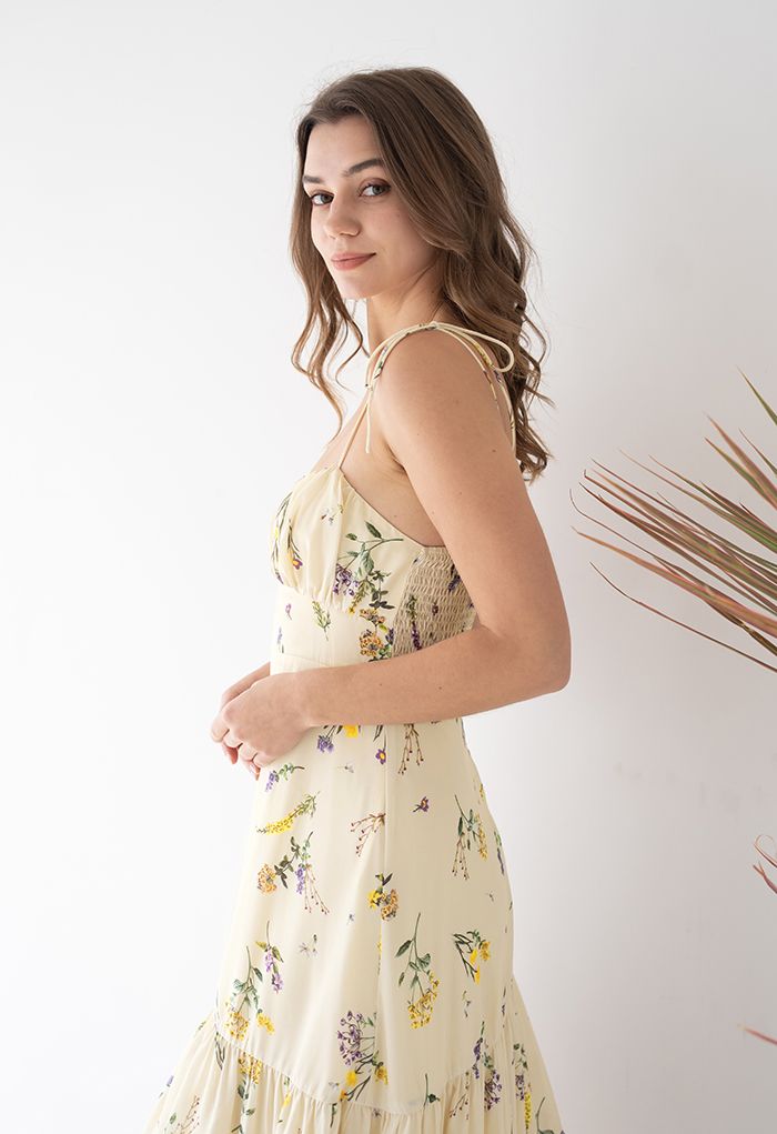 Side view of a woman wearing a romantic wildflower-printed tie-strap cami midi dress, showcasing its delicate floral pattern and flowing design.