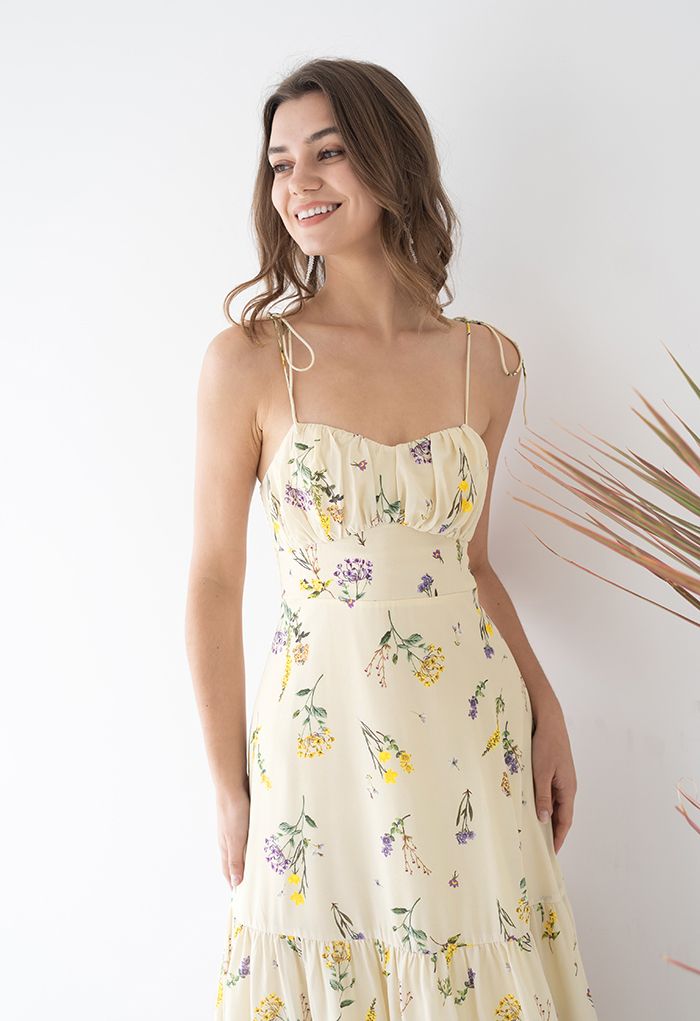 Front view of a woman smiling in a romantic wildflower-printed tie-strap cami midi dress, highlighting its delicate floral design.