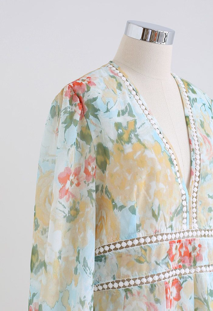 Side view detail of a floral dress with long sleeves, deep V-neck, and lace trim in pastel yellow tones.