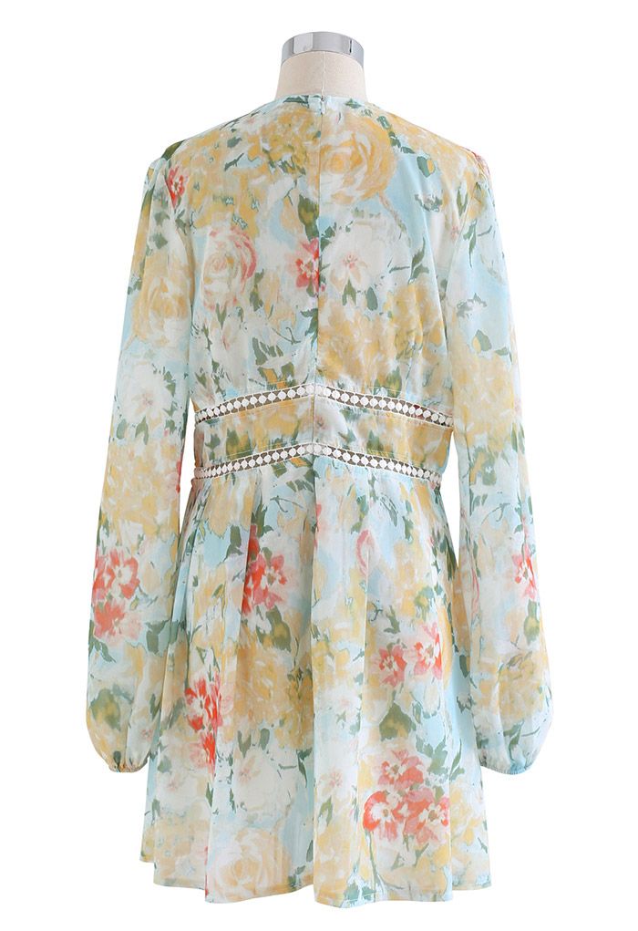 Back view of a floral dress with long sleeves and a deep V-neck, featuring lace trim and a soft yellow floral pattern.