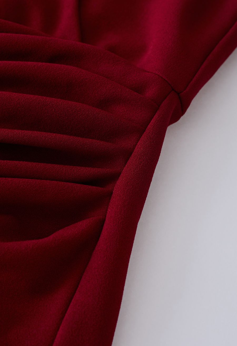 Close-up of the ruched detail on a burgundy dress, emphasizing the stylish and textured design.