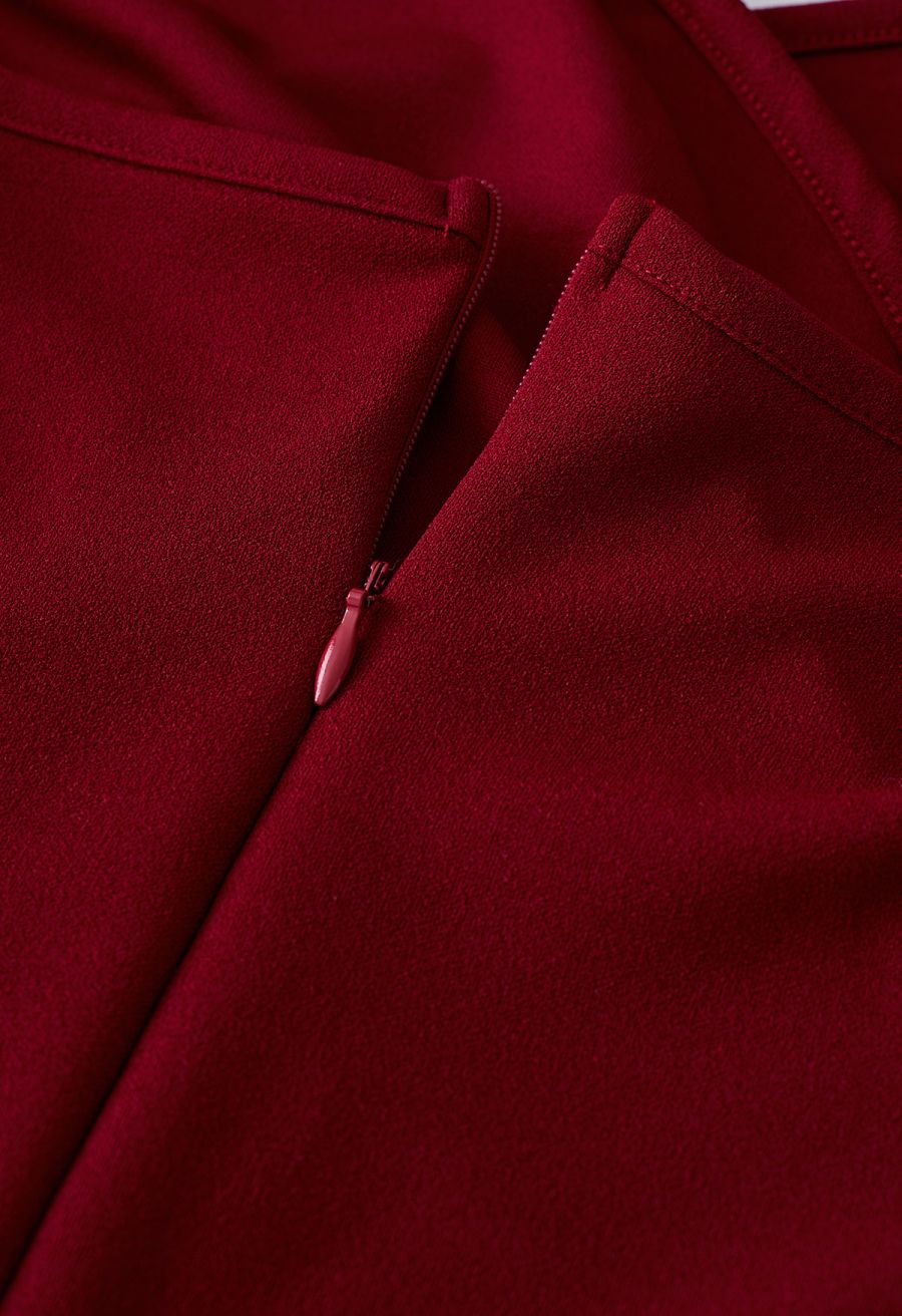 Close-up of the zipper detail on a burgundy dress, emphasizing the smooth texture and precise tailoring.