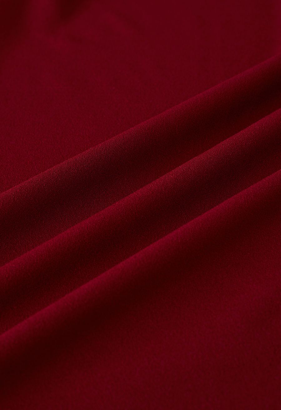 Close-up of burgundy fabric with a luxurious and rich texture, highlighting the dress material.