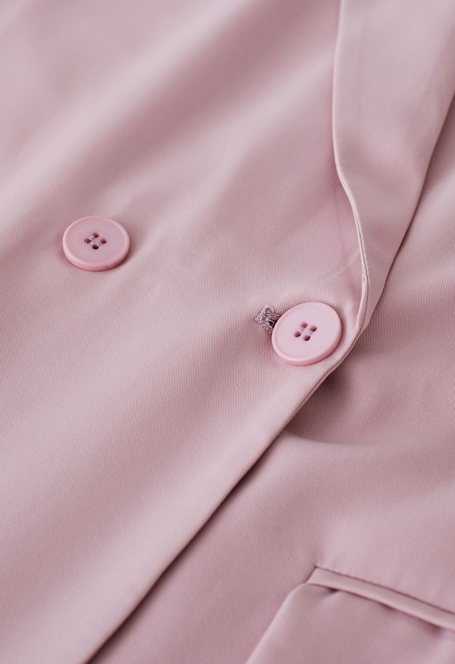 Detail shot of a pink short-sleeve blazer highlighting the buttons and fabric texture, offering a close-up of its refined finish.