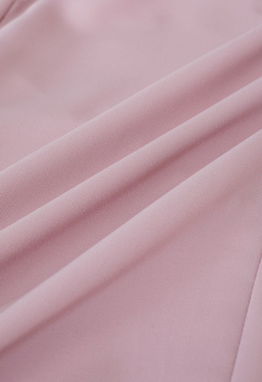 Detail shot of a pink blazer fabric, showing the soft and flowing material in a delicate fold.