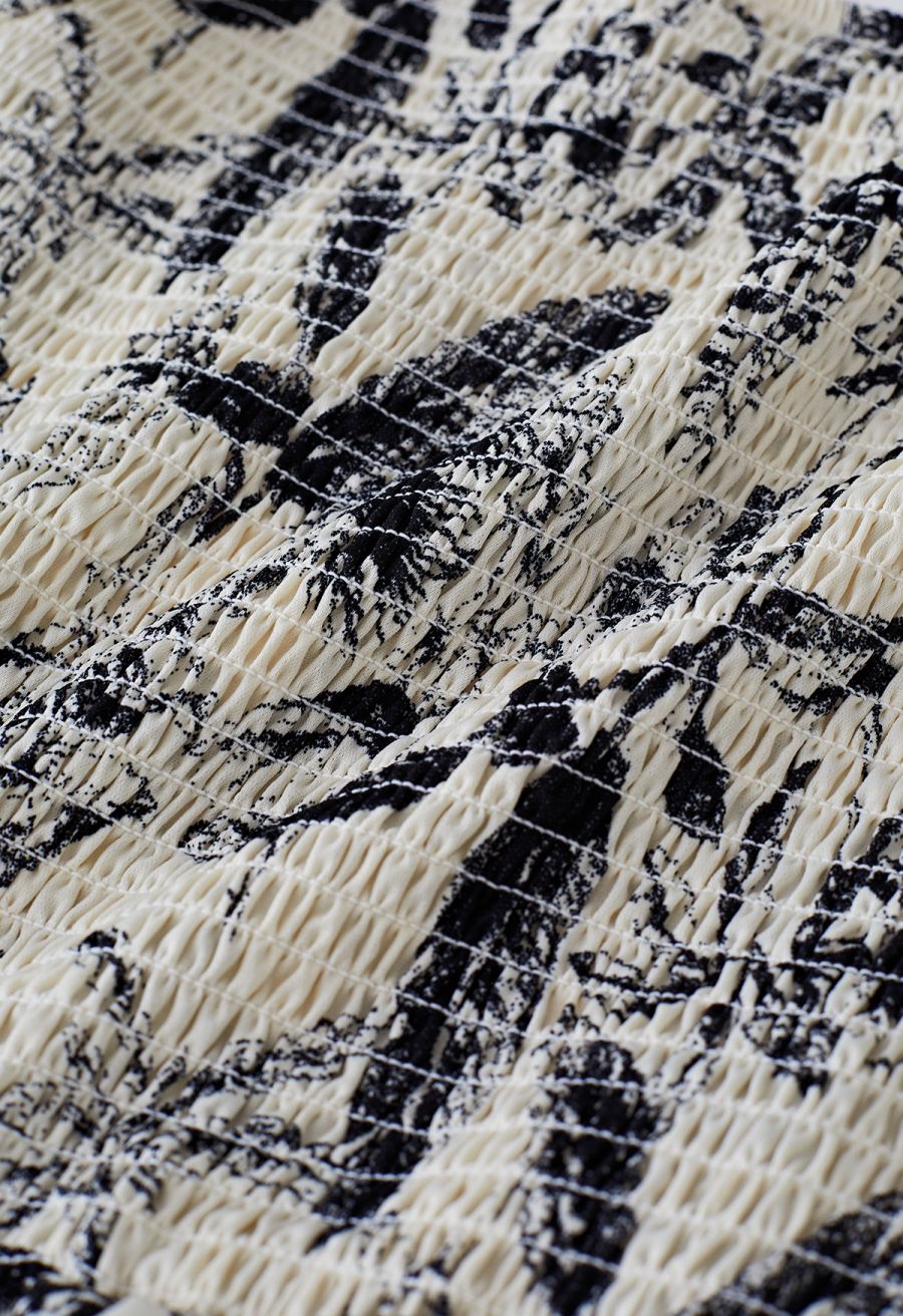 Close-up of the textured smocked fabric with a black and white botanical print on the dress.