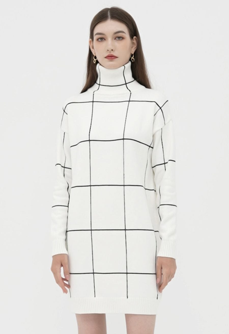 Front view of a model in a white turtleneck sweater dress with a black grid pattern, offering a sleek and stylish look.