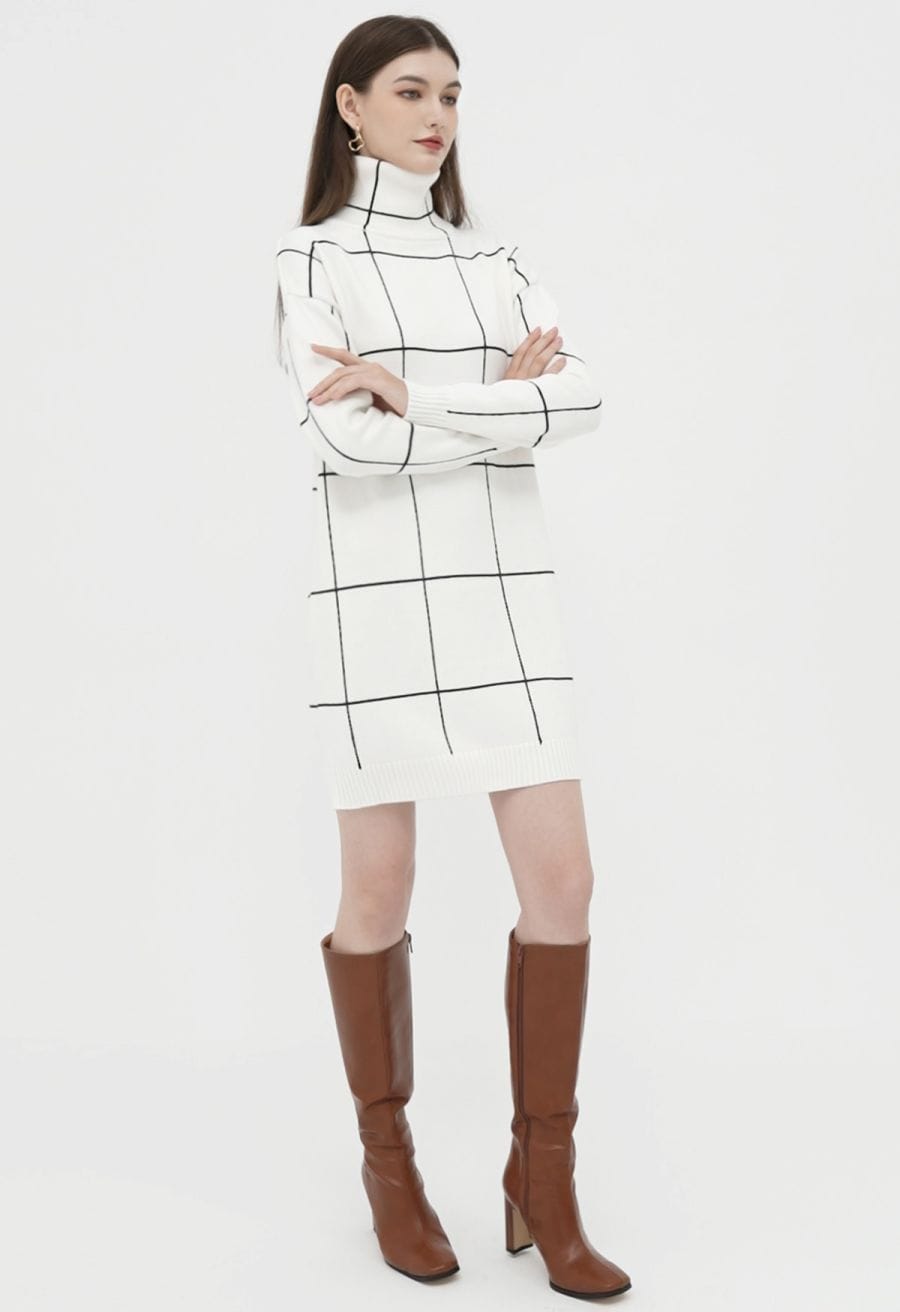 A woman in a white turtleneck sweater dress with a black grid pattern, paired with brown knee-high boots in an outfit shot.