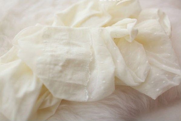 Close-up view of soft, white tights with a delicate dotted texture, showcasing their cozy and elegant material.