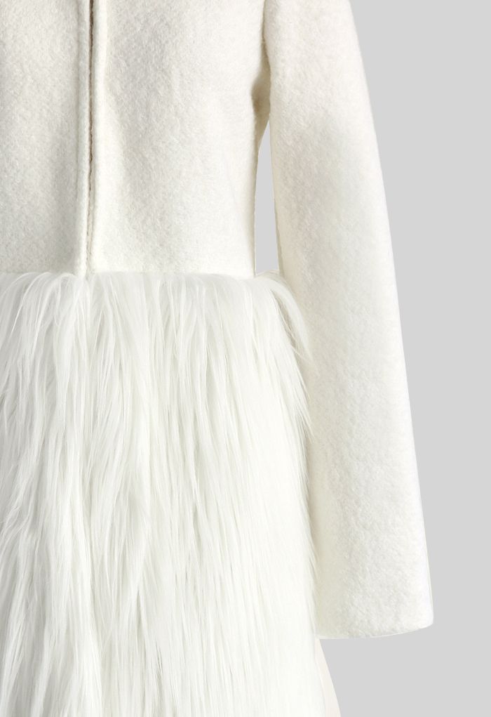 Detail shot of a chic winter essential faux fur coat, focusing on the textured white fabric and soft fur trim.