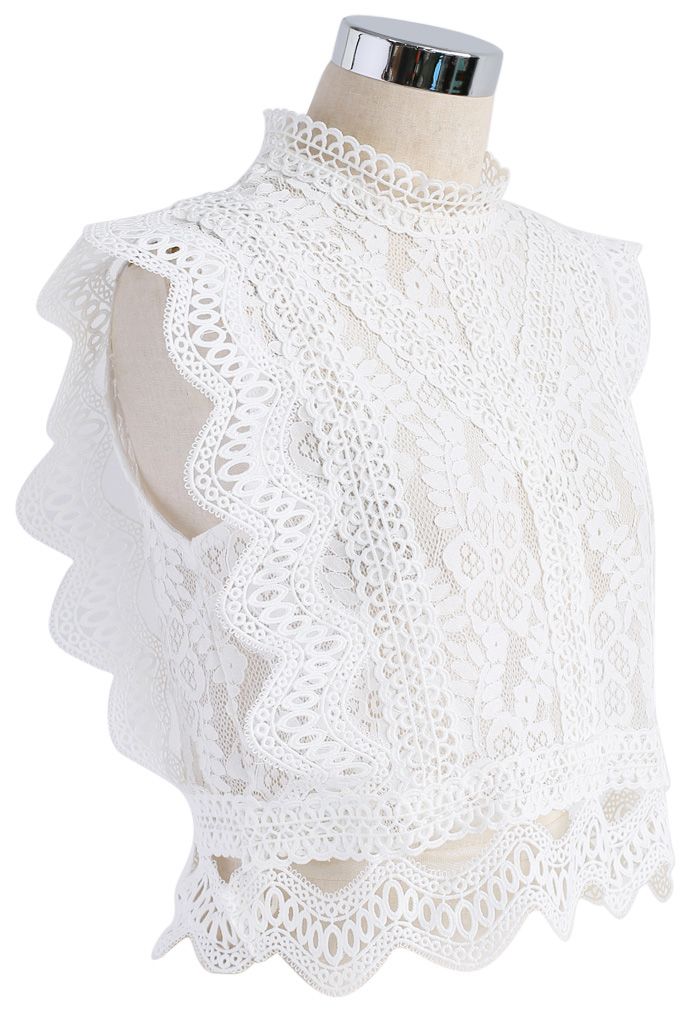 Side view of a sleeveless white crochet lace top showcasing detailed floral patterns and scalloped edges.