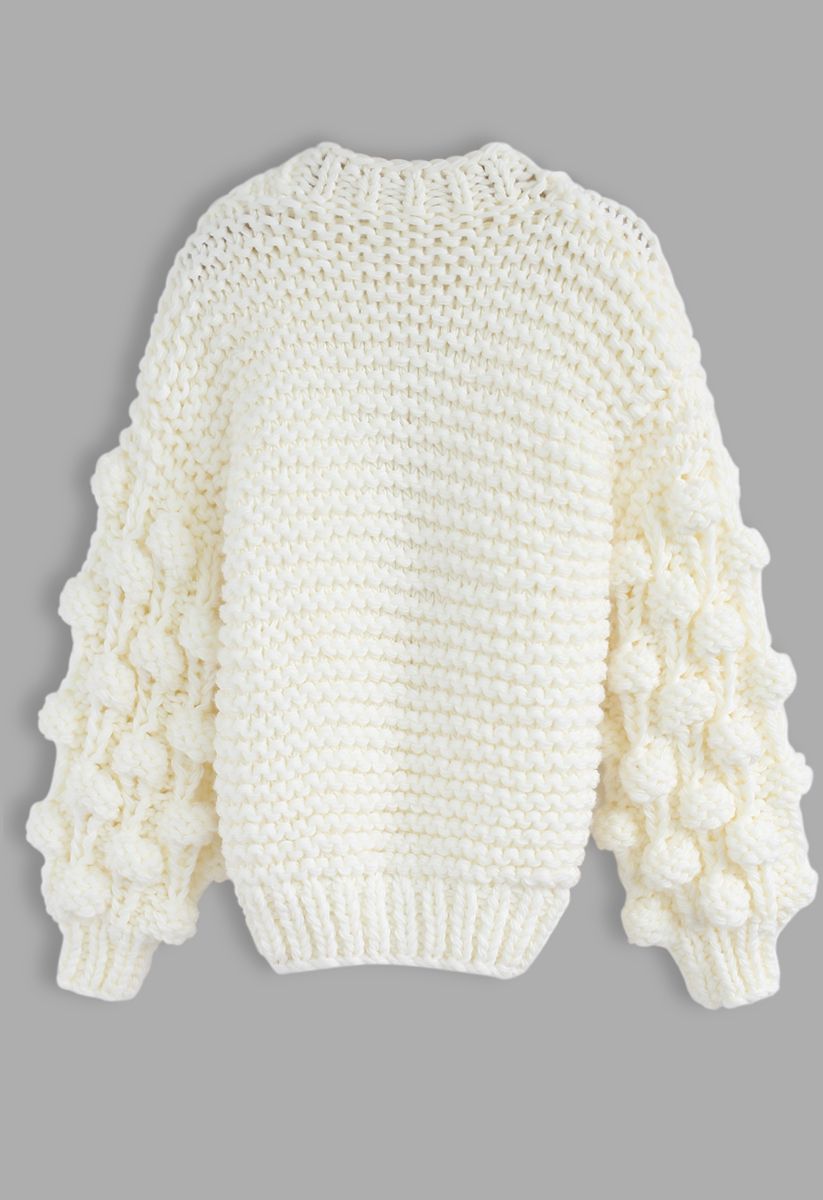 A chunky white cardigan with bubble sleeves, shown in a back view, highlighting its cozy knit texture.