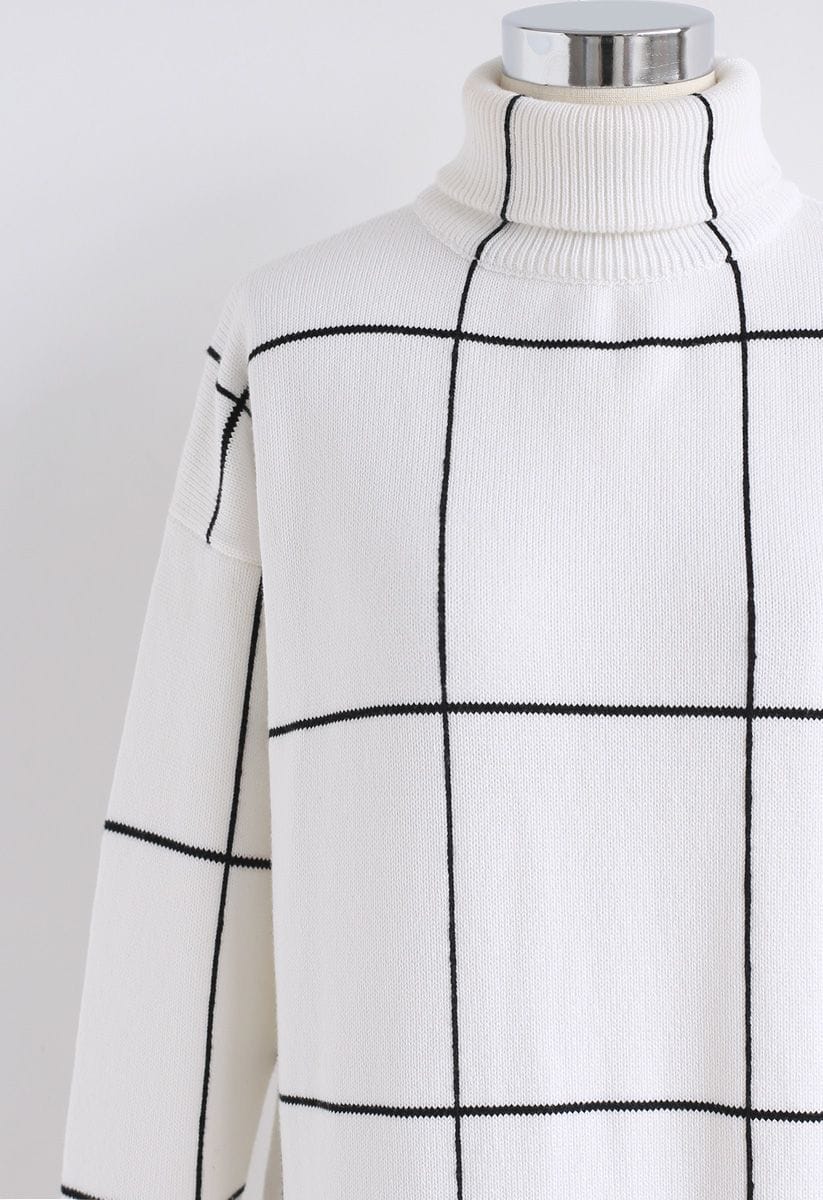 Detail shot of a white turtleneck sweater dress with a black grid pattern, showcasing its modern design.