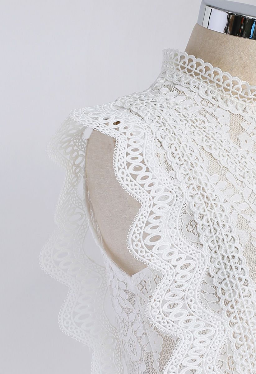 Close-up of a white crochet lace top showing the delicate floral lace and scalloped shoulder detail.