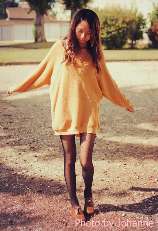 A person wearing French romantic tights with a cozy oversized sweater, standing outdoors in a relaxed pose.